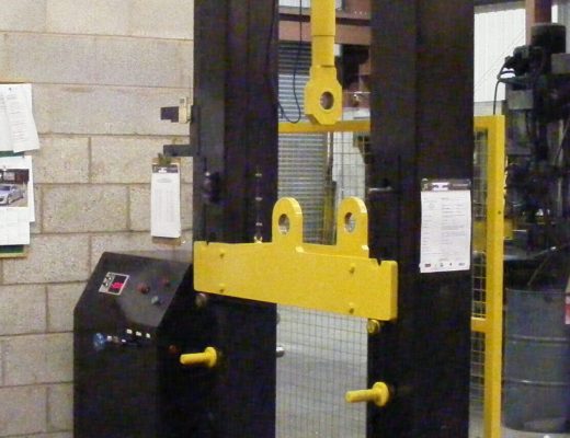 Black vertical tensile test machine with added manual chain hoist to assist set up of machine